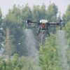 DJI Agras T40 Price and Equipment Package Options A professional DJI Agras T40 agricultural drone in mid-air flight spraying crops over a green field, highlighting its coaxial twin-rotor setup and payload tank configuration for commercial buyers checking the price.
